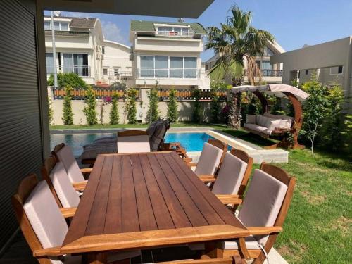 una mesa de madera y sillas junto a una piscina en Sunny Villa Belek, en Belek