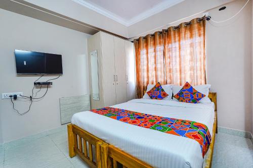a bedroom with a large bed with a tv on the wall at FabHotel Lepsi Inn in Bangalore