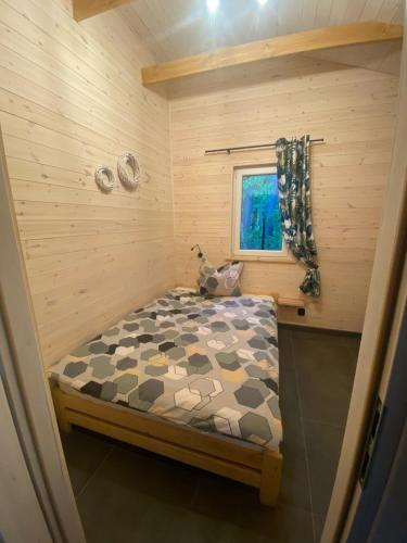 ポゴジェリツァにあるDomki Leśny Zakątekの窓付きの客室の小さなベッド1台分です。