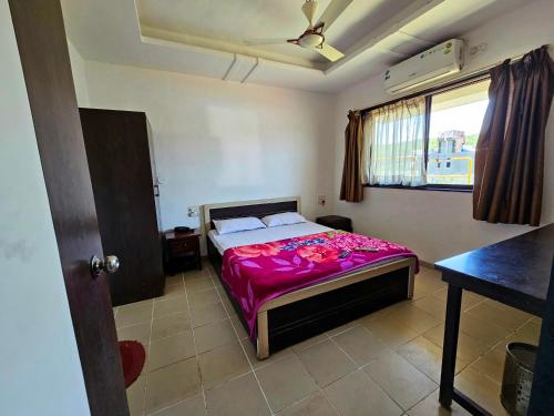 a bedroom with a bed with a pink blanket at Suman Cottage & Bungalow in Mahabaleshwar