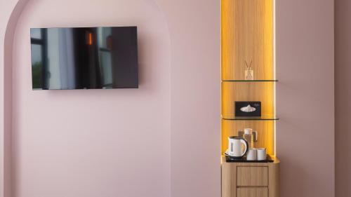 a room with a tv and a coffee maker on a shelf at Wellesley Hotel in Simpang Ampat