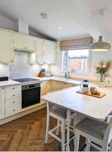 a kitchen with white cabinets and a table with chairs at Palm Cottage in Kent