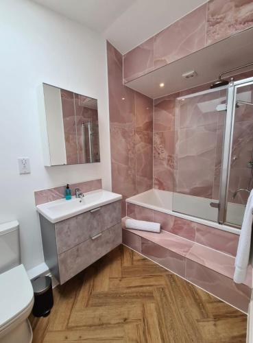 a bathroom with a tub and a sink and a toilet at Palm Cottage in Kent