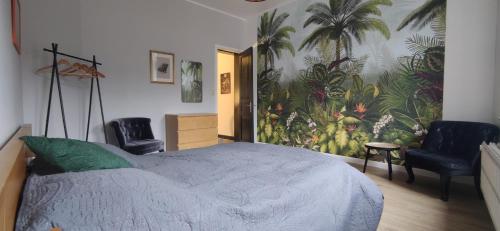 een slaapkamer met een groot bed en 2 stoelen bij Aux frais de la princesse - Gîte citadin 3 épis in Chimay
