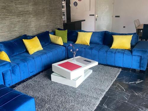 - un canapé bleu avec des oreillers jaunes et une table basse dans l'établissement Superbe appartement meublé à louer avec piscine, à Harhoura