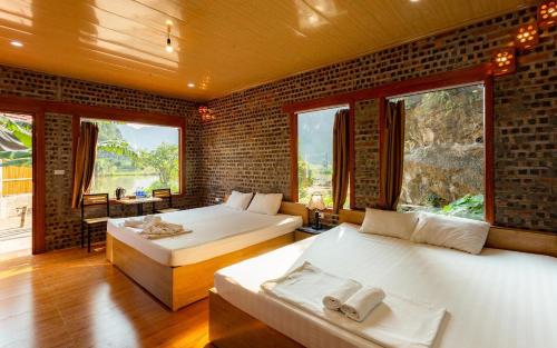 two beds in a room with two windows at Ham Rong Bungalow in Xuân Sơn