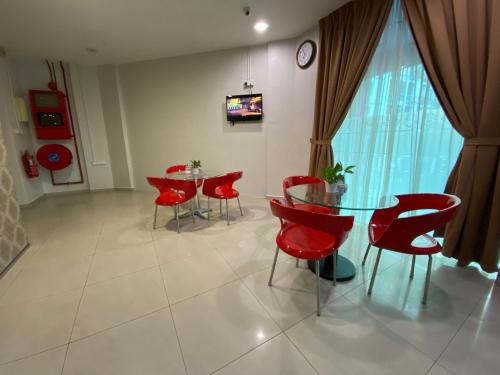 a dining room with red chairs and a glass table at Sweet Memories Hotel in Melaka