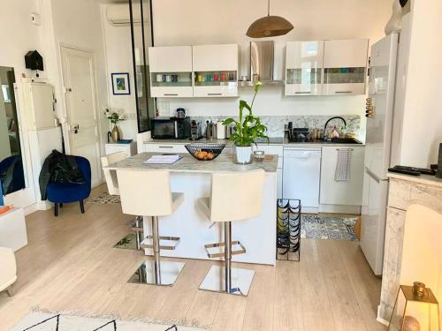 une cuisine avec des armoires blanches et une table avec des chaises dans l'établissement Paca Properties -12CV- T2 Cosy, à Cannes
