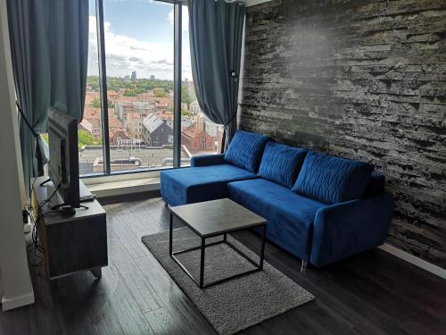 a living room with a blue couch and a large window at City Apartment in Klaipėda