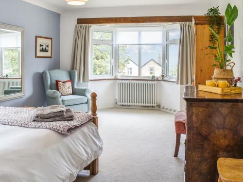 a bedroom with a bed and a chair and windows at Little Saxby in Crowborough