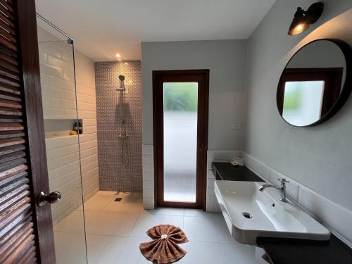 a bathroom with a sink and a shower and a mirror at Silan Residence, Koh Phangan - An authentic village experience in Chaloklum