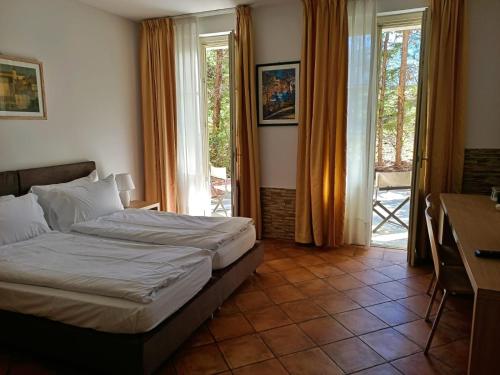 a bedroom with a bed and a desk and windows at Aquazzurra Resort & Aparthotel in Cannobio