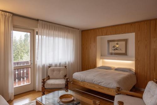 1 dormitorio con 1 cama, 1 silla y 1 ventana en Sorapis Mini - Monolocale Panoramico, en Cortina dʼAmpezzo