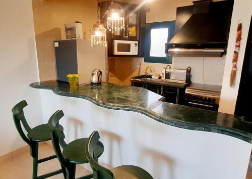 a kitchen with a counter and two green chairs at La Hacienda ras sedr chalet in Ras Sedr
