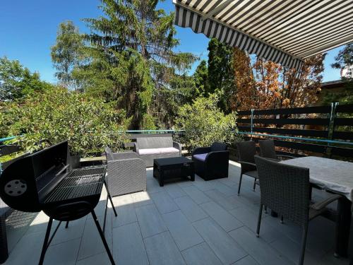 een patio met stoelen, een tafel en een parasol bij Tisch Vendégház in Hajdúszoboszló