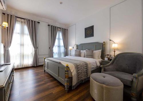 a bedroom with a large bed and a chair at Le Thatluang D'oR Boutique Hotel in Vientiane