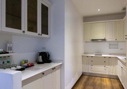 a white kitchen with white cabinets and a wooden floor at Le Thatluang D'oR Boutique Hotel in Vientiane