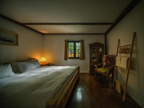 a bedroom with a large bed and a chair at Deep Breath B&B in Fengshan