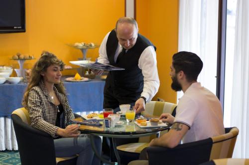 a man holding a plate of food at a table at Hotel Giglio in Montecatini Terme