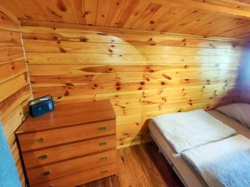 1 dormitorio con 1 cama y pared de madera en DOM LAS 2-natura, relaks, jacuzzi, akwen Jeziorsko en Kolonia Strachocice