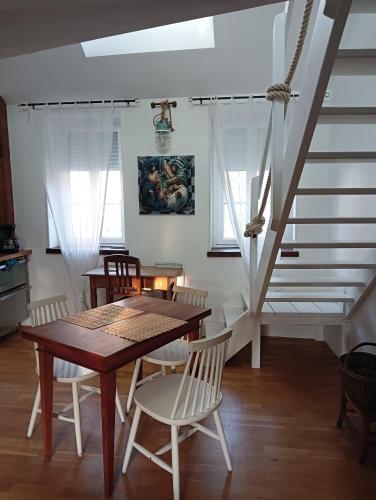 une salle à manger avec une table et des chaises et un escalier dans l'établissement La Baleine - Hyper centre, Charme et calme à deux pas de la mer, à Cabourg