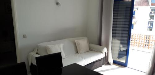 um sofá branco numa sala de estar com uma janela em Apartamento T1 - Orlamar em Vila Nova de Cacela