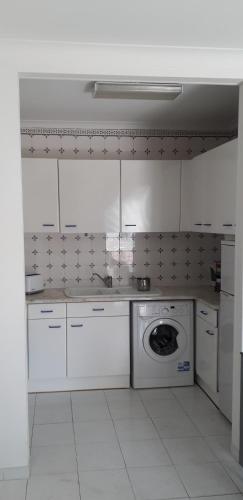 uma cozinha branca com uma máquina de lavar roupa em Apartamento T1 - Orlamar em Vila Nova de Cacela