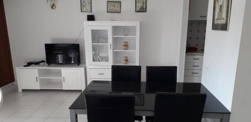 uma sala de jantar com uma mesa e uma televisão em Apartamento T1 - Orlamar em Vila Nova de Cacela