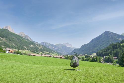 a sculpture in a field with mountains in the background at Eco-Green Fiores Agriturismo in Vigo di Fassa