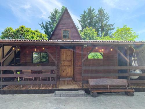 eine große Holzhütte mit einer Veranda und einem Dach in der Unterkunft DOM LAS - natura, relaks, jacuzzi. in Mianów