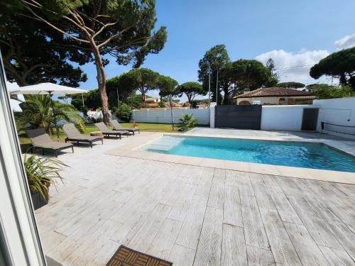 a swimming pool in a yard with chairs and a house at Villa Yoli 26 con Piscina y Jardin cerca de la Playa in Chiclana de la Frontera