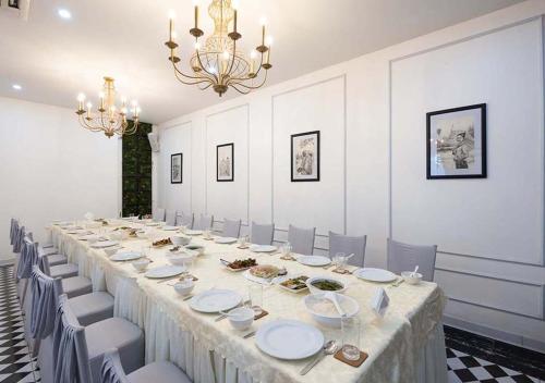 a long table in a room with chairs and a chandelier at Le Thatluang D'oR Boutique Hotel in Vientiane