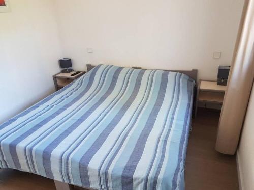 - une chambre dotée d'un lit avec des draps rayés bleus et blancs dans l'établissement A 2 min des plages Clim parking, à Sainte-Maxime