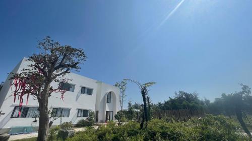 a white building with trees in front of it at Dreamers Farm in Vinh Thanh