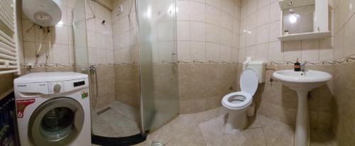 a bathroom with a toilet and a sink and a washing machine at Boulevard Mitrovica in Mitrovicë