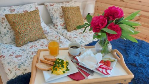 a tray of breakfast food on a bed with a vase of flowers at Słoneczna Chata z Bali in Lądek-Zdrój