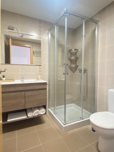 y baño con ducha, aseo y lavamanos. en PreaMar apartamento acogedor con terraza, en Laxe