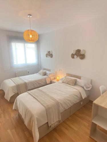 2 camas en una habitación con paredes blancas en PreaMar apartamento acogedor con terraza, en Laxe