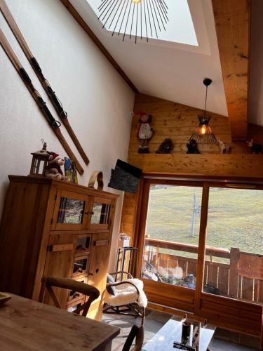 une salle à manger avec une grande fenêtre et une table dans l'établissement Appartement Schuss II vue montagne au pied des pistes, à Flumet