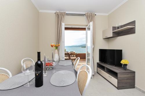 a dining room with a table with a bottle of wine at Apartmani Perić 1 Meka Draga in Obrovac