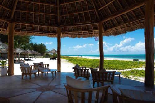 un restaurante en la playa con mesas y sillas en Amani Boutique Hotel - Small Luxury Hotels of the World en Paje