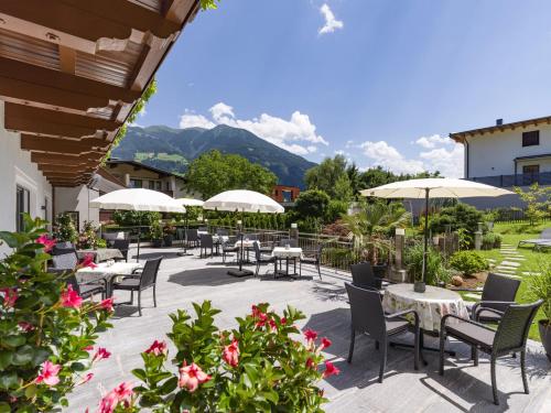 een patio met tafels, stoelen en parasols bij Hotel Landhaus Zillertal in Fügen