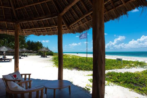 a beach with a table and chairs and the ocean at Amani Boutique Hotel - Small Luxury Hotels of the World in Paje