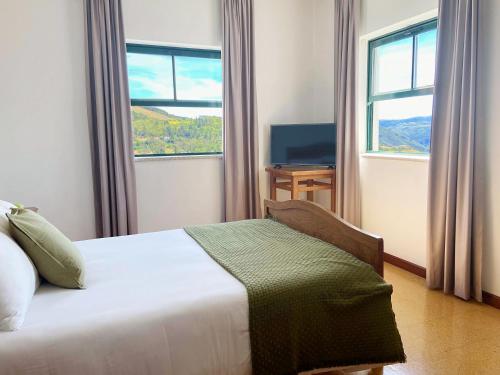 a bedroom with a bed and two windows and a television at Vinhais Hotel in Vinhais