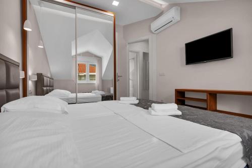 Habitación blanca con 2 camas y TV. en Brotis - Apartment with sea view en Promajna