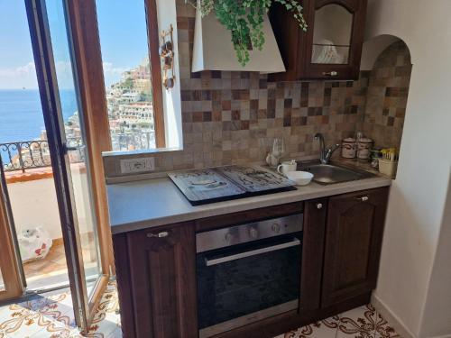 cocina con fogones, fregadero y ventana en Estate4home - MAISON LIRIO en Positano
