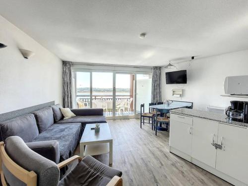 un salon avec un canapé bleu et une cuisine dans l'établissement V-Marin 04-Vieux Boucau Appartement 2 chambres avec superbe vue sur le lac marin dans une résidence avec piscine, à Vieux-Boucau-les-Bains