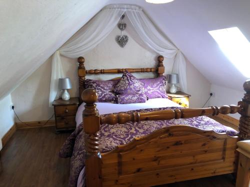 a bedroom with a wooden bed with a canopy at Mc Courts Cottage in Hilltown
