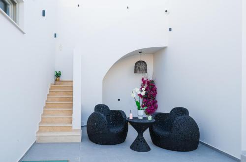 a room with two black chairs and a table with flowers at La Madeleine Oia in Oia