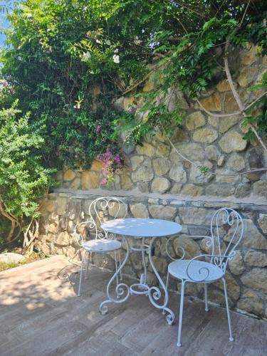 a table and two chairs next to a stone wall at La Rocca Maison de Charme in Moneglia